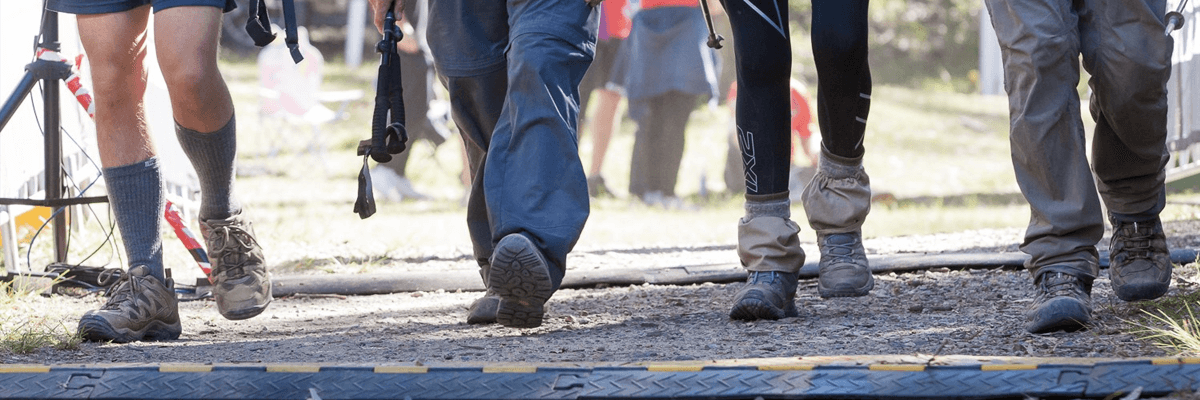 Close up shot of four people walking along a dirt path in hiking boots
